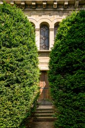 Catholic-church;-Christianity;-Corbelled-cornice;-Green-archway;-Kaleidos;-Kaleidos-images;-La-parole-à-limage;-Modillion;-Neo-Romanesque;-Places-of-worship;-Religion;-Religious-architecture;-Religious-building;-Round-arched-window;-Saint-Pierre-de-Montrouge-church;-Side-door;-Stained-glass;-Stone-step;-Stories-Pictures;-Tarek-Charara;-Wooden-door;-Yew-hedge